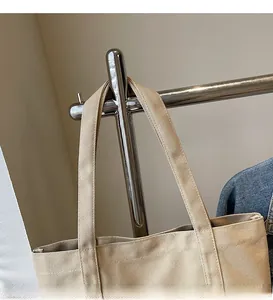 Vue détaillée du sac cabas en toile beige montrant les longues bandoulières robustes