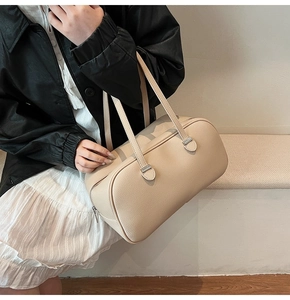 Detail of cream-colored pebble leather tote bag featuring elegant silver metal hardware
