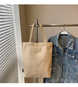 Gros plan sur le sac fourre-tout en toile beige avec poignées renforcées et étiquette latérale