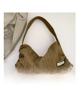 Detail of pleated shoulder bag with SUPERIOR label and side drawstring on khaki fabric