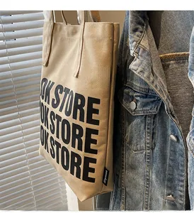 Détail du sac cabas en toile avec typographie bookstore noire et étiquette logo