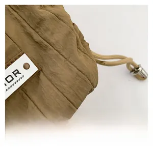 Detail of brown quilted fabric bag featuring a drawstring closure and logo patch