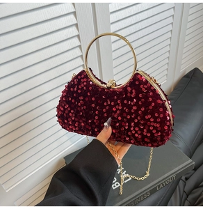 Close-up of burgundy sequins evening bag with a golden ring handle and ball clasp