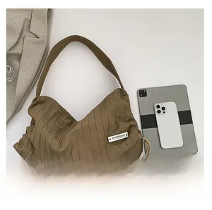 Detail of khaki pleated shoulder bag showing spacious interior with tablet and phone