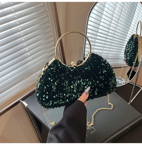 Detail of dark green sequin clutch bag with golden ring handle and chain strap