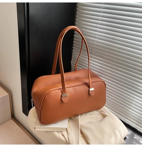 Detail of caramel lychee grain leather pillow bag with natural light on metal strap buckle