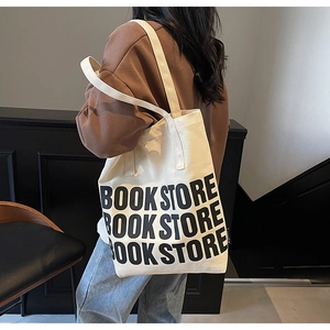 Détail du sac cabas en toile avec imprimé BOOK STORE porté par un mannequin