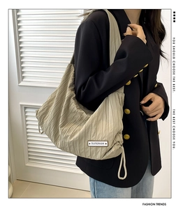 Detail of beige pleated tote bag featuring drawstring side and Superior fabric label
