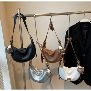 Detail of four textured hobo bags in black, brown, silver and white with plush charms