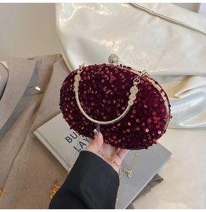 Detail of burgundy sequin evening bag featuring ornate gold flower handle and rhinestone clasp