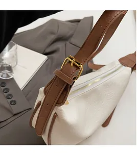 Close-up of white lychee leather bag with adjustable brown strap and gold metal buckle