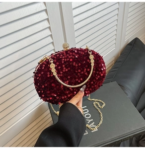 Close-up of sparkling burgundy sequin evening clutch bag with gold handle and jewel clasp