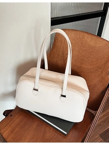 Cream-colored lychee textured Boston bag with top handles on a wooden chair