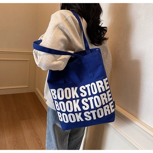 Détail du sac cabas en toile bleu roi avec imprimé BOOK STORE et étiquette tissée latérale