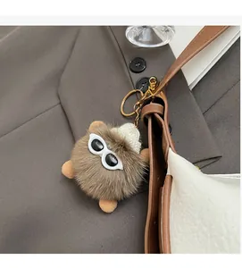 Brown fluffy monster bag charm with sunglasses and white knit hat on a shoulder strap