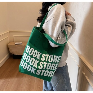 Détail du sac cabas en toile verte avec lettrage BOOK STORE blanc et bandoulière large