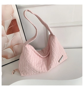 Detail of pink pleated canvas tote bag featuring superior logo and wide shoulder strap