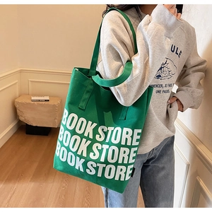 Détail du sac cabas en toile verte avec lettrage Book Store blanc et texture épaisse