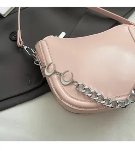 Detailed close-up of a pink saddle bag with a silver chain and crescent pendants