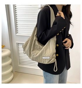 Detail of beige pleated tote bag featuring drawstring base and SUPERIOR label design