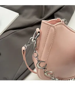 Detail of pink leather saddle bag with silver metal chain link hardware and neat stitching