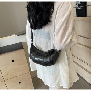 Close-up of black crinkled leather crescent bag showing rich texture and adjustable strap