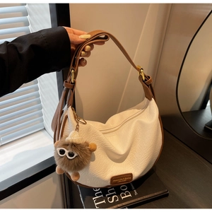 Detail of white moon bag with lychee texture, brown trim and plush charm detail