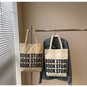 Détail du cabas en toile avec inscription BOOK STORE sur une matière texturée
