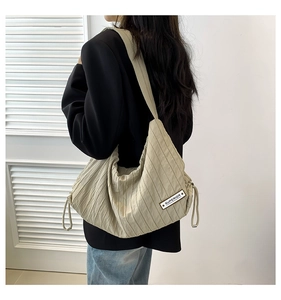 Outdoor view of beige pleated shoulder bag showing size and capacity on a model
