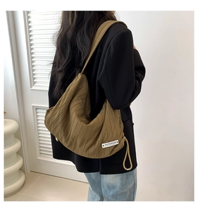 Detailed view of large pleated canvas tote bag with black SUPERIOR label on olive green fabric