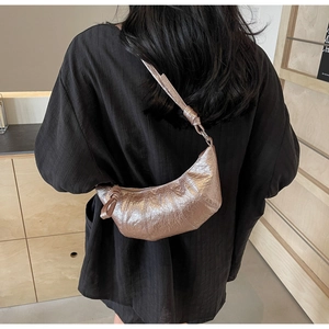 Detail shot of the metallic croissant bag featuring pleated texture and knot shoulder strap