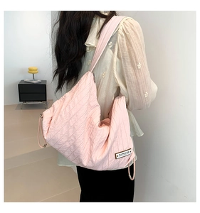 Close-up of pink quilted crossbody bag with 'SUPERIOR' label worn by model
