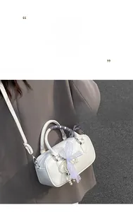 Détail du sac à main bowling blanc avec foulard à carreaux et breloque en dentelle