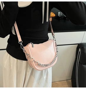 Detail of light pink faux leather crossbody bag with silver chain and moon pendant