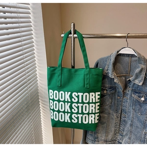 Détail d'un sac cabas en toile verte avec imprimé BOOK STORE dans un cadre de vie moderne