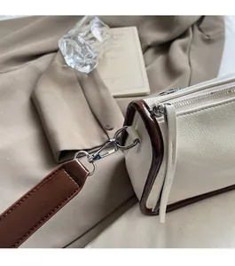 Gros plan d'un sac crème avec des bords marron foncé et des détails métalliques argentés