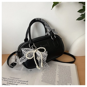 Close-up of black bowling bag with pearl lace bow charm and ribbon wrapped handle