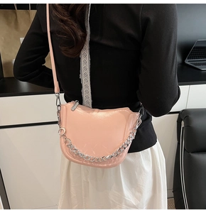 Detail of pink patent leather saddle bag with silver metal chain and shoulder strap