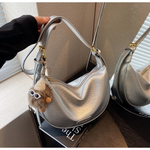 Detail of silver grained leather hobo bag with zip closure and plush monster charm