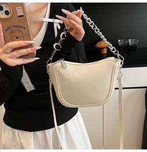 Detail of beige U-shaped leather shoulder bag with silver chain handle and C pendants