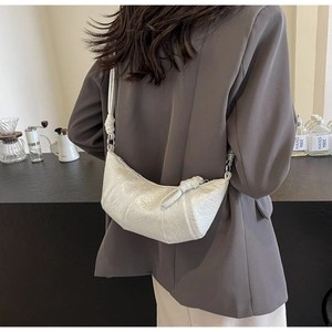 Detail of white moon bag featuring crackle texture leather and knot strap design