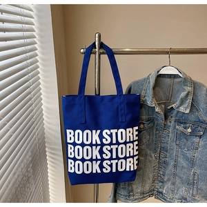 Sac cabas en toile bleue avec inscription BOOK STORE suspendu dans un décor épuré