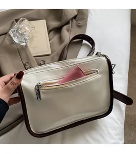 Vue détaillée de la poche arrière zippée du sac bandoulière en cuir verni blanc avec porte-carte