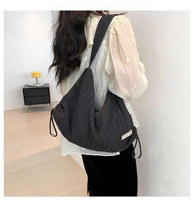 Detail of black pleated canvas tote with drawstring side and superior logo patch
