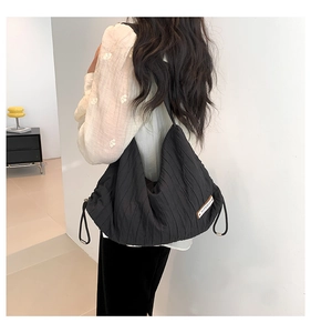 Detail of black pleated hobo bag with side drawstring and superior brand patch