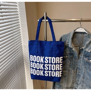 Détail du sac fourre-tout bleu roi avec lettrage Book Store blanc et anses en toile épaisse