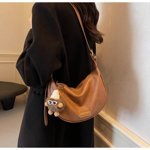 Detail of caramel lychee leather crescent bag with adjustable strap and plush charm