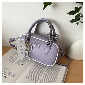 Detail of lavender Boston bag with white piping and decorative scarf on wood surface