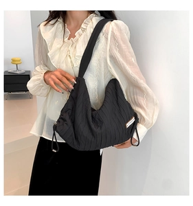 Close-up of black pleated nylon tote bag with white SUPERIOR label detail