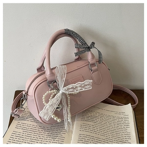 Pink Boston handbag detail with lace bow, pearl heart charm, and plaid wrapped handles